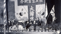 Ceremony on the second anniversary of the March 1st Movement at the Olympic Theater on Jingansi-lu, Shanghai (March 1, 1921). President Yi Seungman and State Council members participated. In this picture, Kim Byeongjo is reading the Declaration of Independence. From left: Shin Gyusik, (unknown), Bak Eunsik, (unknown), Kim Byeongjo, Yi Seungman, Jang Bung, Yi Dongnyeong, Ahn Changho