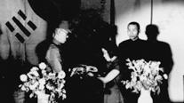 Min Yeongju presenting flag to Commander-in-Chief Yi Cheongcheon. From left: Yi Cheongcheon, Min Yeongju, Kim Gu